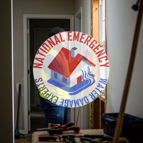 Water damage restoration technician working in a Norland, FL property, featuring the National Emergency Water Damage Experts logo, tools for cleanup, and an interior setting indicative of water damage response.